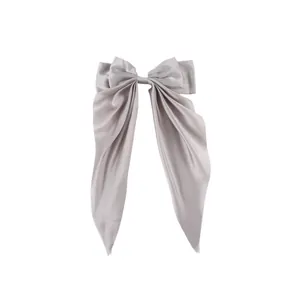 Detail of a large silver-grey satin bow hair clip with long ribbons on white background