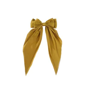 Close-up of mustard yellow satin bow hair clip with elegant long hanging ribbons