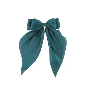 Detail of the oversized dark teal satin bow hair clip with smooth glossy ribbon texture