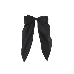 Detail of elegant black satin bow hair clip with long ribbons and smooth texture