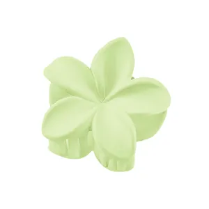 Detail view of a matte mint green plumeria flower hair claw clip on white background