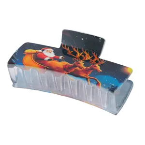 Close-up of frosted Christmas hair claw clip featuring Santa and reindeer night scene