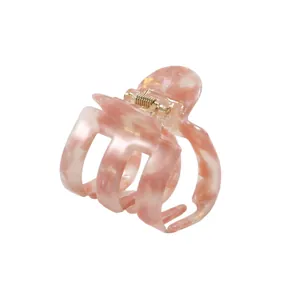 Dettaglio della pinza per capelli in acetato marmorizzato rosa con molla in metallo oro