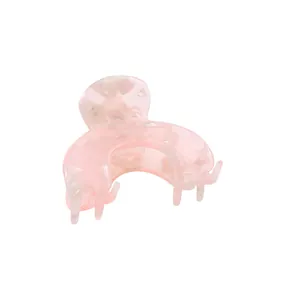 Detail of pink marble textured acetate hair claw clip with glossy finish for styling
