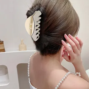 French style cream acetate hair claw clip holding a sleek low bun hairstyle