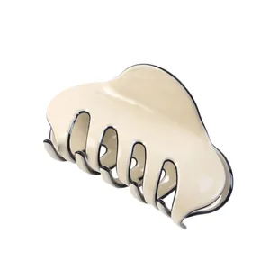 Close-up of cream hair claw clip with black edges showing glossy resin texture