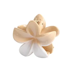 Detailed view of a gradient white plumeria flower hair claw clip with a matte finish