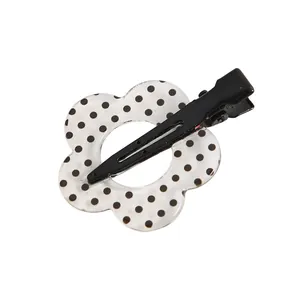 Detalle de pinza para el pelo con forma de flor blanca y lunares negros con clip de metal
