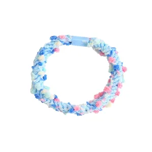 Détail d'élastique à cheveux en peluche bleue avec pompons colorés et attache plastique