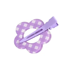 Detalle de una pinza para el pelo con forma de flor lila y patrón de cuadros morados