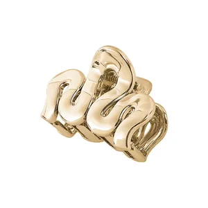 Close-up of golden metal claw clip with minimalist wave design and polished mirror finish