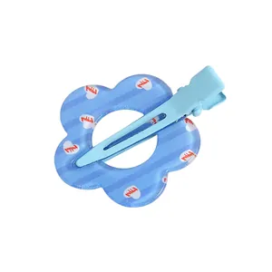 Detalle de la pinza de pelo flor azul de acrílico con corazones blancos y texto Happy