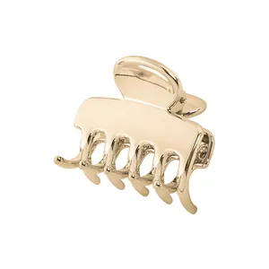 Detailed view of polished gold metal hair claw clip with interlocking teeth on white background