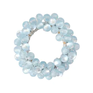 Detail of light blue cat-eye stone elastic hair tie with translucent beads and silver thread