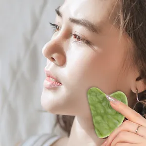 Dettaglio della pietra gua sha in giada verde a forma di cuore per massaggio viso