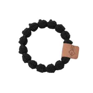 Détail d'un élastique en tissu noir avec étiquette en cuir à motif de lapin