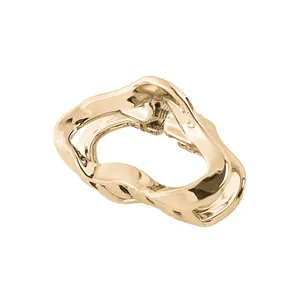 Detailed close-up of a minimalist gold metal hair claw clip with a wave-shaped cutout design