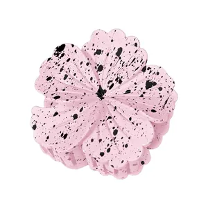 Detail view of 8cm pink plumeria flower hair claw with artistic black ink splatter pattern