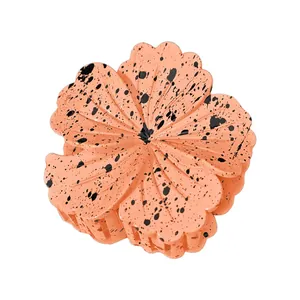 Detail of peach orange plumeria hair claw clip with black ink spots and 3D floral petals