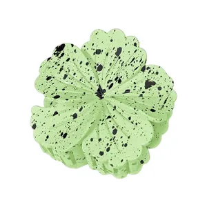 Detailed view of light green plumeria hair claw clip with black speckled petal patterns
