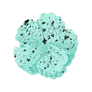 Close-up of a mint green flower hair claw clip with unique black ink splatter texture