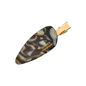 Minimalist tortoiseshell acetate hair clip with gold metal clasp for women on white background