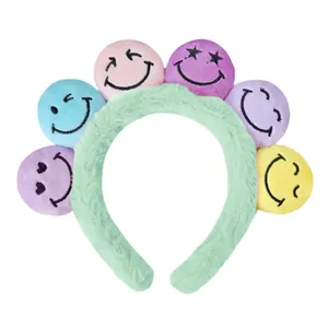 Nahaufnahme von minzgrünem Plüschstirnband mit bunten, bestickten Smiley-Gesichtsbällen