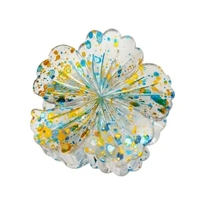 Close-up of a transparent acrylic flower hair claw clip with vibrant colorful ink splashes