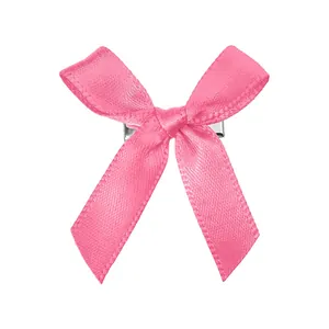 Gros plan détaillé d'une barrette nœud en satin rose avec clip en métal argenté