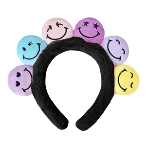 Detailansicht eines bunten Plüschstirnbands mit verschiedenen gestickten Smileys