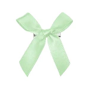 Détail de la pince à cheveux nœud en satin vert clair avec texture soie et clip métal