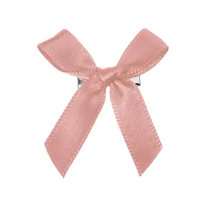 Détail d'une pince à cheveux avec nœud en satin rose doux et base métallique
