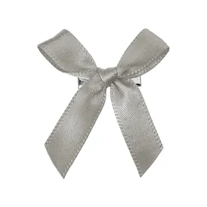 Détail d'une pince à cheveux à nœud en satin gris avec ruban soyeux et base en métal