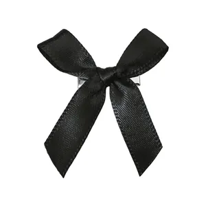 Détail d'une pince à cheveux à nœud en satin noir avec un clip en métal argenté poli