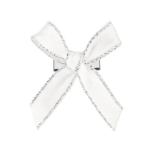 Détail d'une pince à cheveux nœud blanc avec des bords scintillants en paillettes argent
