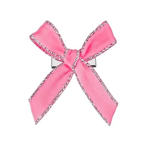 Détail de la pince à cheveux nœud en satin rose avec bords pailletés et clip en métal
