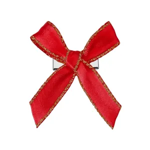 Détail d'une pince à cheveux avec nœud en satin rouge et bordure dorée scintillante