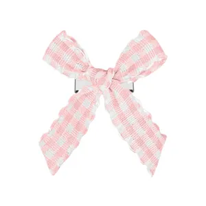 Détail de la barrette nœud à carreaux rose et blanc avec bords ondulés et pince argentée