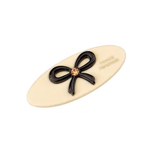 Ovale Haarspange aus Acetat in Creme mit schwarzer Schleife, Bernstein-Stein und Golddruck