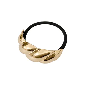Detailansicht eines elastischen Haargummis mit großem goldenem Metallknoten-Element