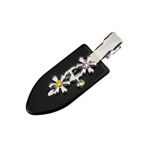 Vue détaillée de la pince à cheveux noire avec fleurs argentées et strass multicolores