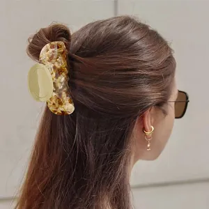 Classic tortoiseshell hair claw clip for women holding a ponytail in a minimalist style