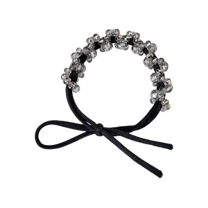 Detail of beaded black elastic hair tie featuring grey crystals and a simple bow design