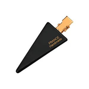 Macro shot of a black triangular acrylic hair clip with gold France Handmade logo