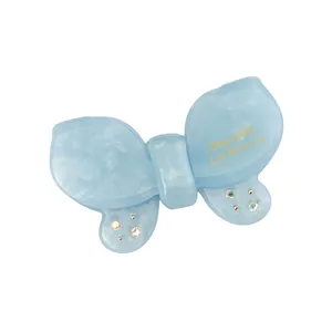 Detail of light blue acetate butterfly hair clip with rhinestones and gold text