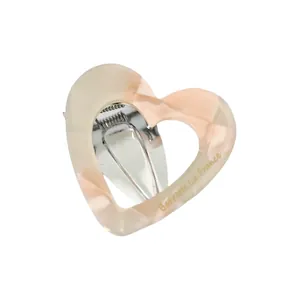 Pink heart-shaped acetate hair clip with marble texture and gold lettering branding