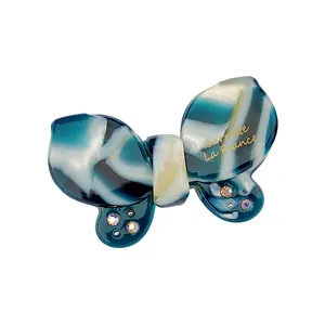 Detail of marble pattern acetate butterfly clip with rhinestones and gold lettering