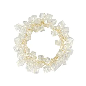 Macro shot of sparkling square crystal beads on a cream elastic hair tie band