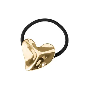 Detalle de goma para el pelo con adorno de corazón dorado en metal líquido pulido