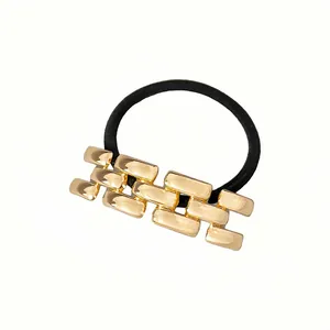 Detalle del adorno metálico dorado en la goma elástica negra para el pelo de alta calidad